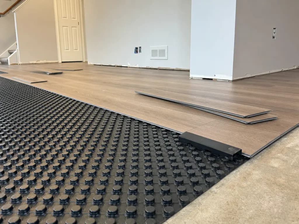 Vinyl plank flooring going down over a dimpled basement subfloor panel