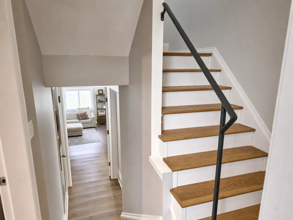 Basement stairs with oak treads, white risers and a black metal handrail