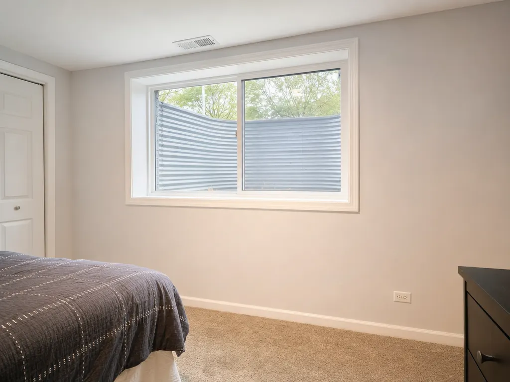 Basement bedroom with a large egress window and a galvanized window well
